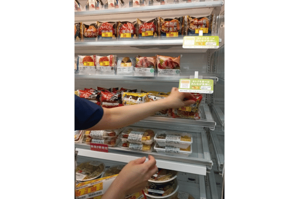 店舗でおにぎりに値引きシールを貼る様子