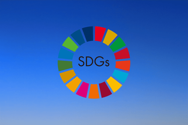 青空を背景に、カラフルなSDGs(持続可能な開発目標)のロゴが中央に配置されている。