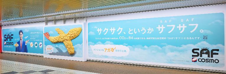 コスモエネルギーホールディングス、超サフサフな「飛行機型巨大エビ天」をモチーフにした屋外広告を新宿駅で掲出開始