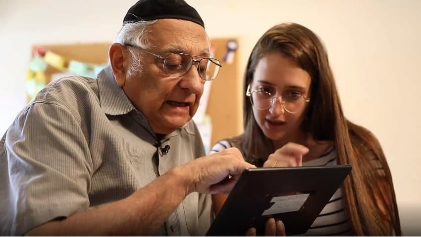 おじいさんと女性がタブレットを一緒に覗き込みながら話をしている写真です。